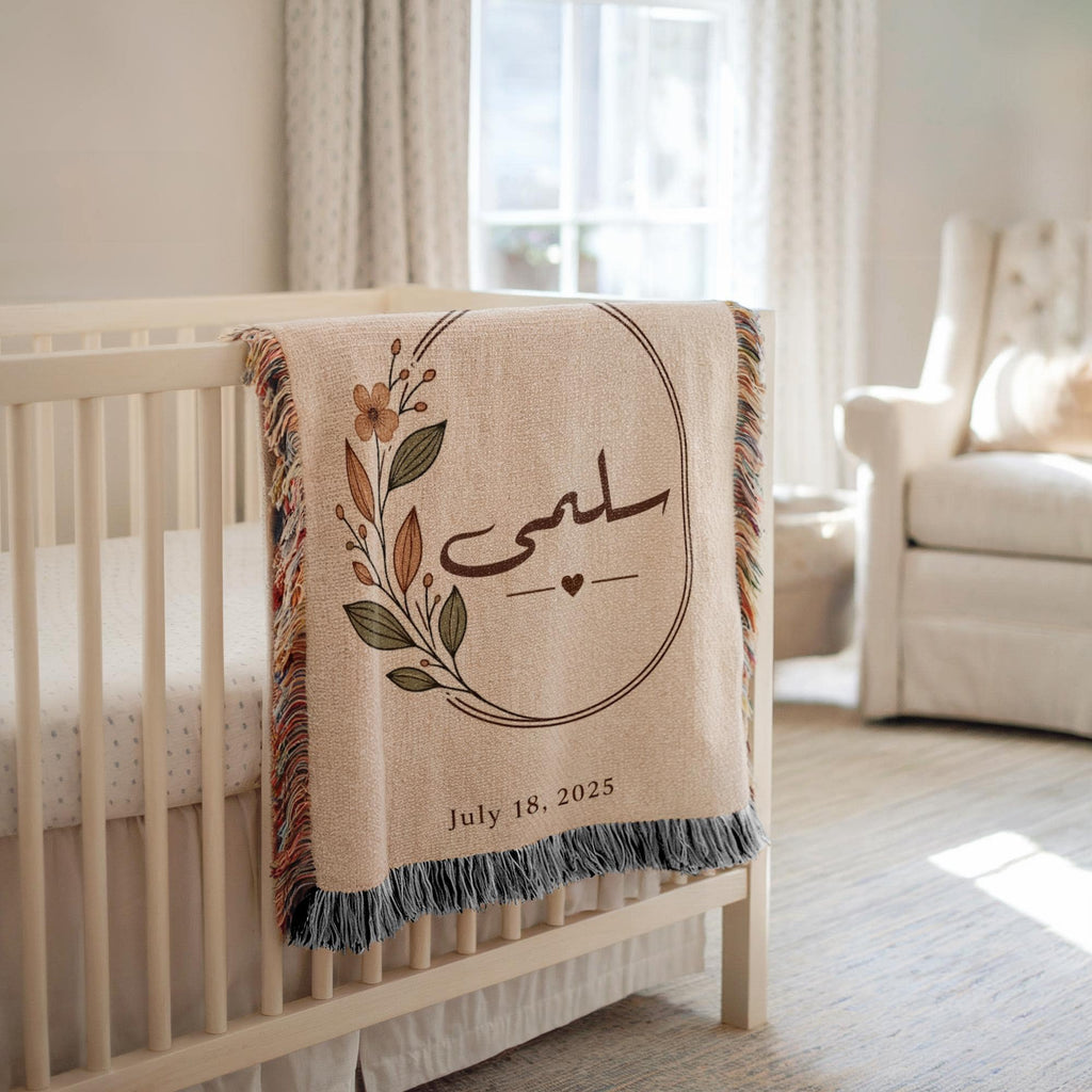 Arabic calligraphy blanket draped over a white crib, with a floral oval frame and date visible, set in a brightly lit nursery background.