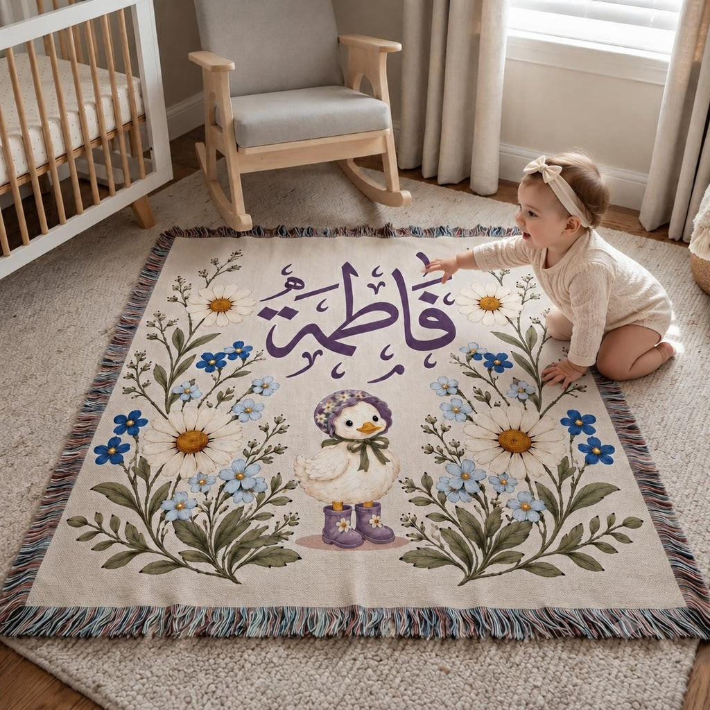A young child sits cross-legged on a customized botanical blanket on a nursery floor, surrounded by its intricate floral design and personalized name. The room has light wood floors and a crib nearby, creating a calm, sunlit atmosphere.