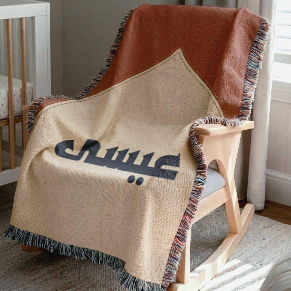 Close-up view of the Mosque Arch Arabic Baby blanket's woven texture, casually draped over a wooden rocking chair.