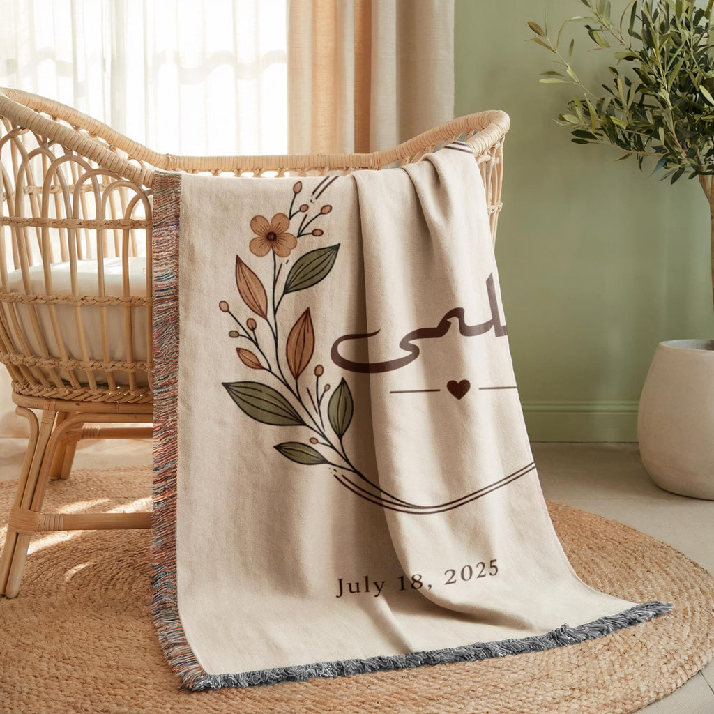 Close-up of the "Botanical" personalized blanket's tasseled fringe, draped over a wooden baby chair in a brightly lit nursery, highlighting the floral design and date.