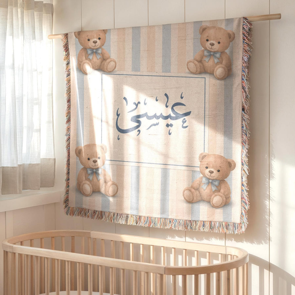 Striped bear patterned baby blanket with custom Arabic name, hanging on the wall as a decorative tapestry above a wooden crib.