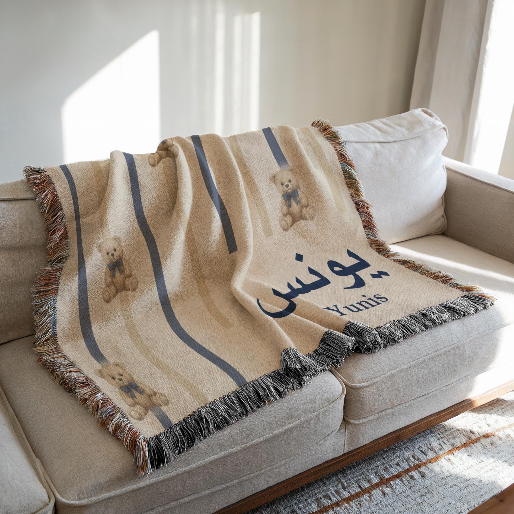 A cream-colored blanket featuring cartoon bears and vertical stripes, draped over a white sofa in a bright, modern living room.