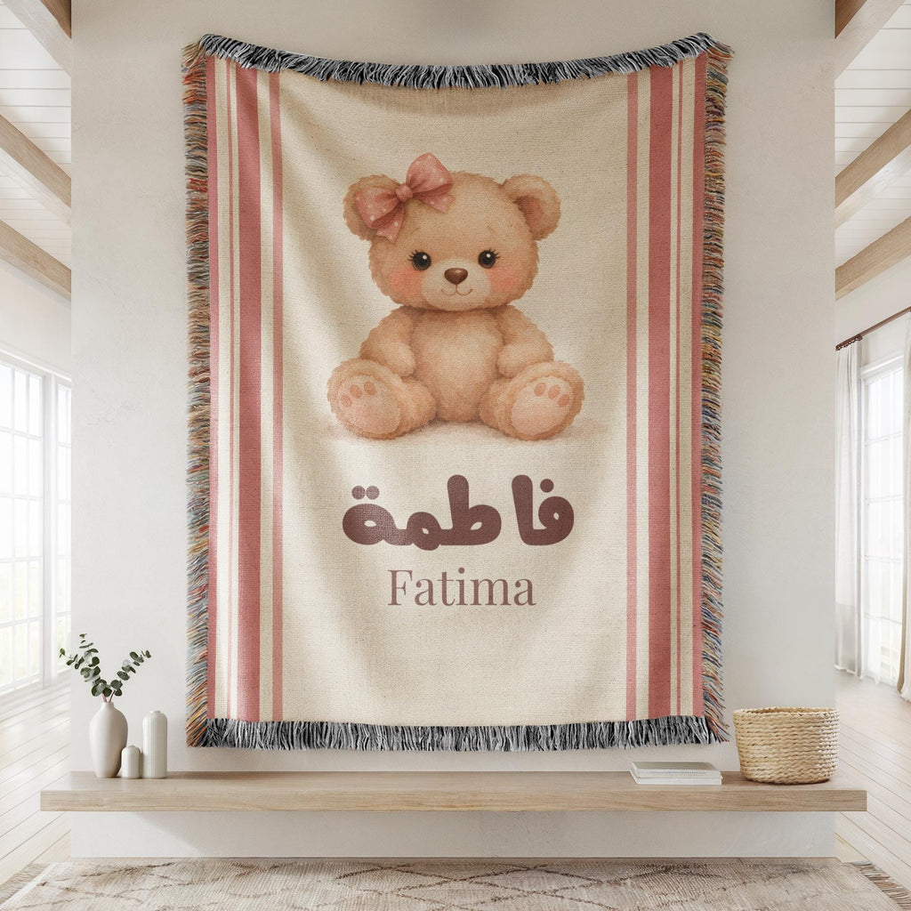 Close-up of the "Vintage Bear" personalized blanket's woven texture, hanging flat against a wall, showing the teddy bear illustration, custom name, and fringed edges.